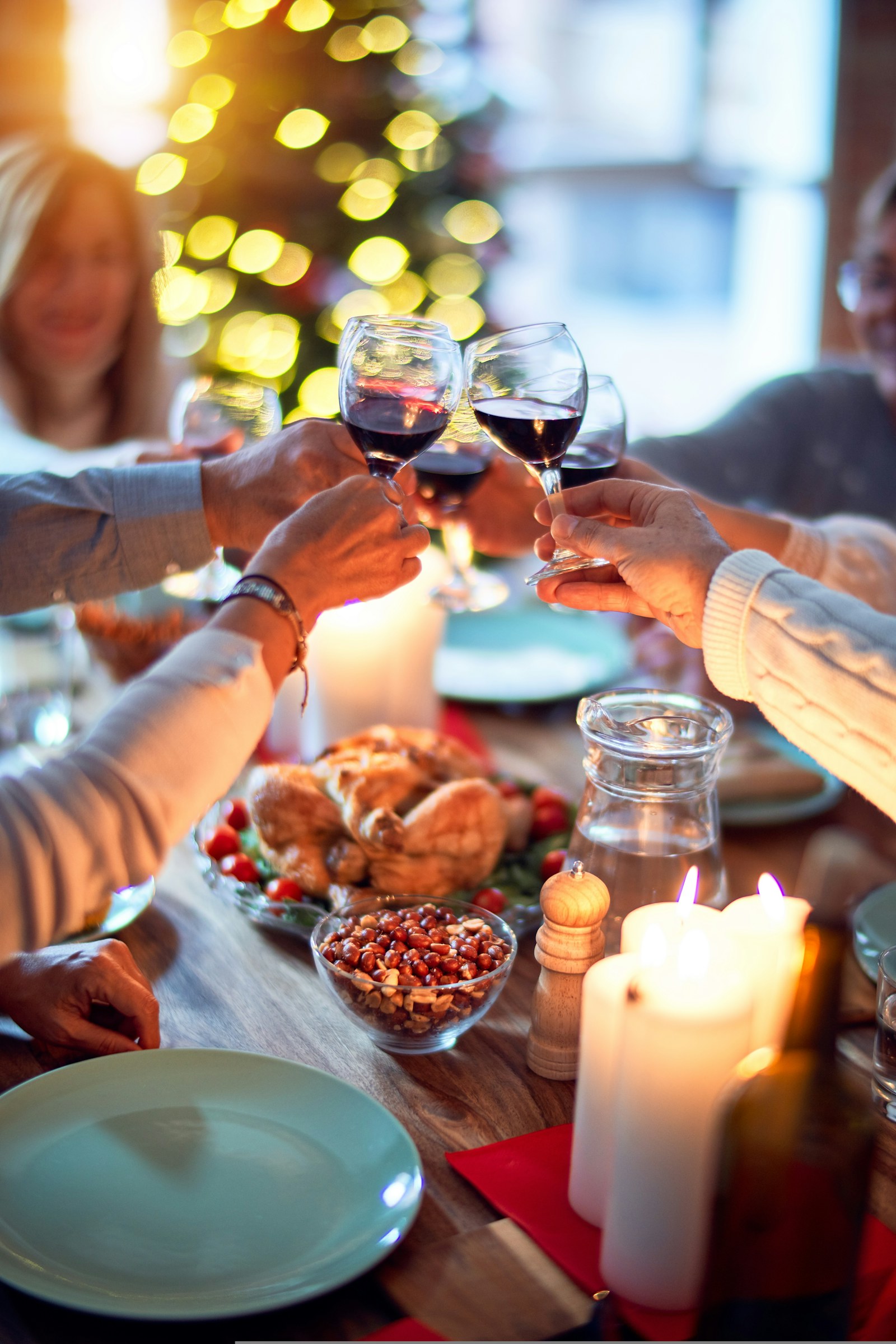 Brindisi con il vino rosso a una tavola apparecchiata per la cena di Natale